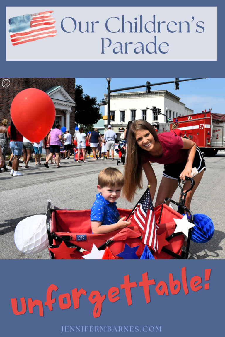 A child sits in a red wagon festooned with patriotic decorations. The words say: Our Children's Parade - Unforgettable."