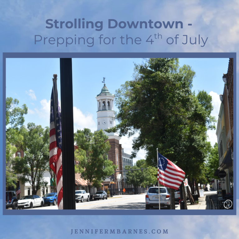 Image of a downtown street decorated with flags everywhere. The header says "Strolling Downtown: Prepping for the Fourth of July"